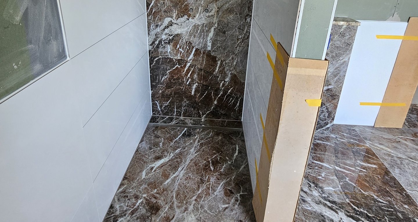 Bodengleiche Dusche mit Edelstahl-Duschrinne und großformatigen Fliesen in Marmoroptik während der Bauphase in Harburg (Schwaben)